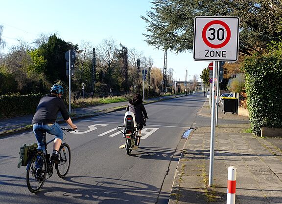 Zwei Radfahrer fahren an einem Tempo 30 Schild vorbei. 