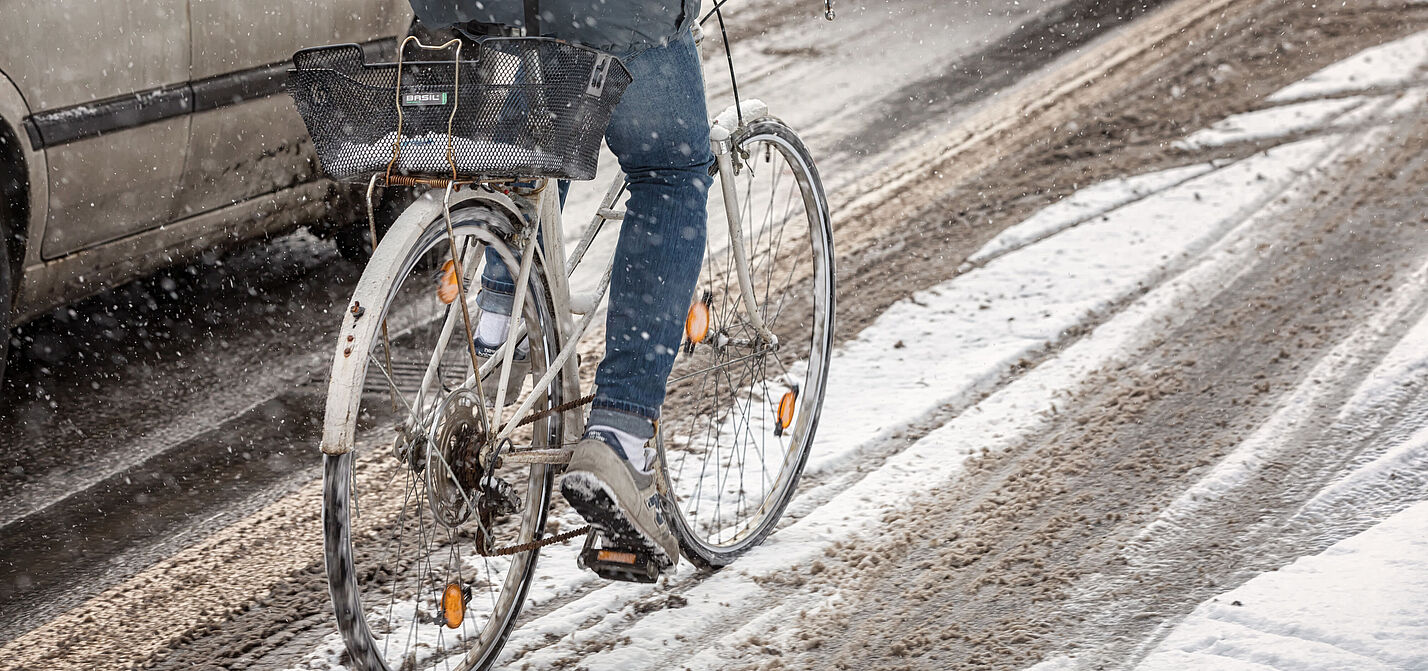 Ein Radfahrer fährt auf einem ungeräumten Radweg durch Schnee.