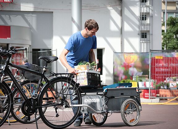 Anhänger Ein Mann belädt einen Fahrradanhänger vorm Supermarkt.